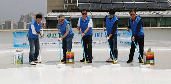 KCC 임직원들이 건물 옥상에 쿨루프 페인트를 시공하고 있다.