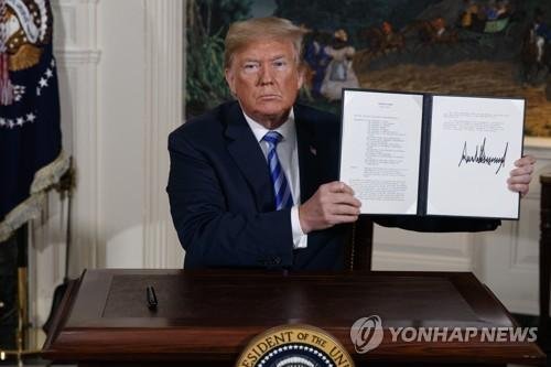 President Donald Trump shows a signed Presidential Memorandum after delivering a statement on the Iran nuclear deal from the Diplomatic Reception Room of the White House, Tuesday, May 8, 2018, in Washington.,AP연합뉴스