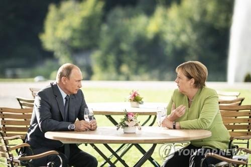 A handout photo made available by the German Federal Government shows Russian President Vladimir Putin (L) and German Chancellor Angela Merkel (R) hold a joint news conference prior to their talks at the German government's guest house Meseberg Palace in Gransee near Berlin, Germany, 18 August 2018.