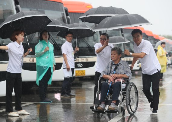 제21차 이산가족 상봉행사 2회차 첫날인 24일 오전 강원도 속초시 한화리조트에서 한 할머니가 우산을 쓴 채 버스로 향하고 있다. 연합뉴스
