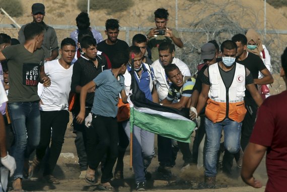 팔레스타인 가자지구 칸유니스의 이스라엘 국경장벽 인근에서 24일(현지시간) 구조대원들이 부상당한 팔레스타인 시위대를 옮기고 있다. 팔레스타인 측은 이날 이스라엘 군이 시위에 나선 약 5000명에게 사격해 최소 50명이 다쳤다고 주장했다.AP연합뉴스