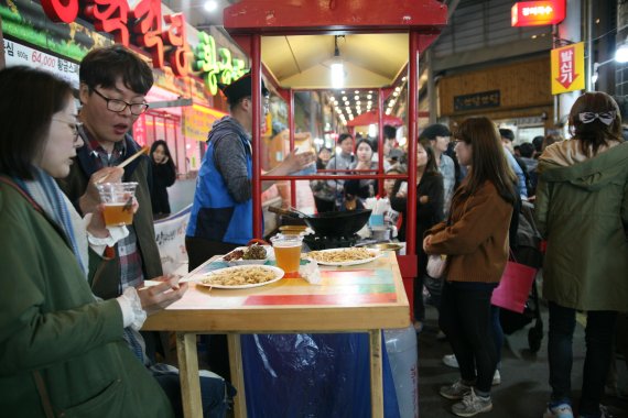 경기 오산시에 위치한 오색시장에서 열린 야시장에서 방문객들이 수제맥주와 함께 주전부리를 먹고 있다.