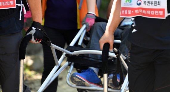 장애인 트레킹용으로 특수제작된 휠체어는 여러 사람이 끌고 밀며 움직인다.