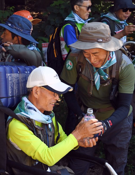 지난 8일 열린 한국트레킹연맹의 북한산 우이령길 산행에서 참가자들이 서로 물을 나눠 마시고 있다.