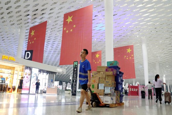 A man carries boxes of goods past Chinese flags at Bao'an international airport in Shenzhen, China September 19, 2018. Picture taken September 19, 2018. REUTERS/Jason Lee <All rights reserved by Yonhap News Agency>