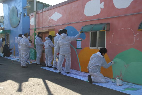 인천도시공사 임직원들이 낙후된 원도심 지역을 생동감 넘치는 동네로 만들기 위해 주택과 담장에 벽화 그리기를 하고 있다.