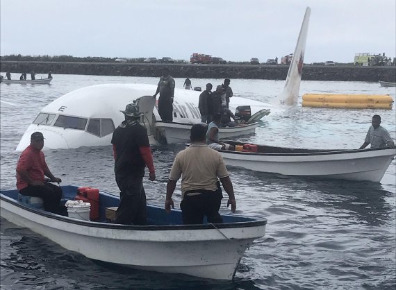 This photo taken by James Benito on September 28, 2018, shows locals approaching the crashed Air Niugini aircraft on the remote Island of Weno, in Micronesia. - An Air Niugini aircraft ditched into a lagoon after overshooting the runway on the remote island of Weno but there were no serious injuries