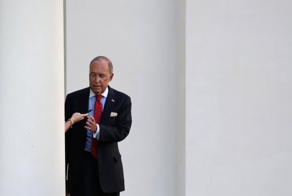 White House economic adviser Larry Kudlow is handed a cellphone from an aide while walking to an interview with Fox News at the White House in Washington, U.S., October 2, 2018. REUTERS/Leah Millis <All rights reserved by Yonhap News Agency>