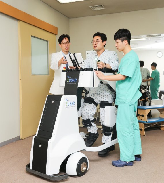 중앙대병원 재활의학과 범재원 교수(왼쪽 첫번째)가 하지재활 환자에게 보행보조로봇 '슈바'를 이용해 재활운동을 돕고 있다.