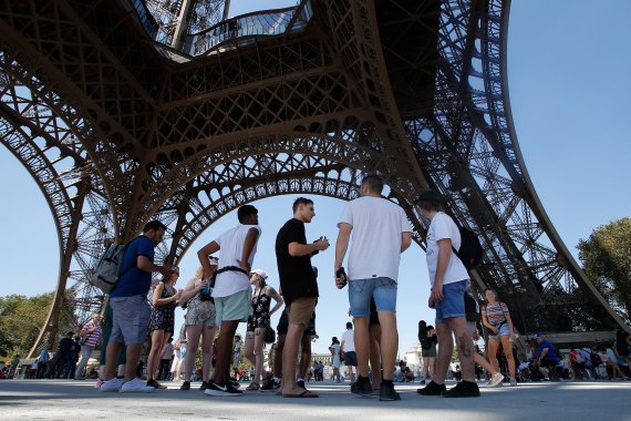 Tourists stand under the Eiffel Tower, Thursday, Aug. 2, 2018 in Paris. (AP Photo/Michel Euler) <All rights reserved by Yonhap News Agency>