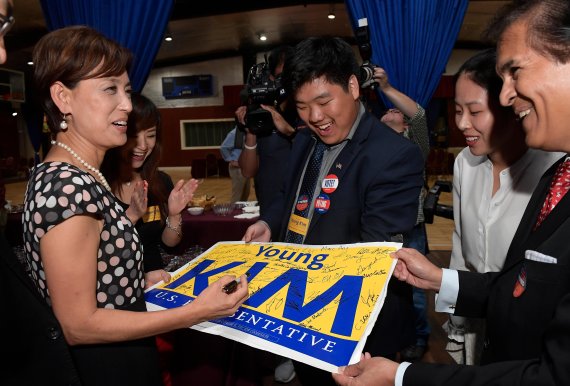 Young Kim, left, Republican candidate for the 39th Congressional District in California, autographs a campaign sign for supporters as she makes a post-midnight appearance without declaring victory, early Wednesday, Nov. 7, 2018, in the Riowland Heights section of Los Angeles. (AP Photo/Mark J. Terri
