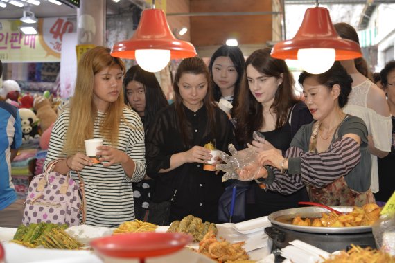 외국인 관광객들이 인천 주안동에 위치한 신기문화관광시장을 찾아 튀김음식을 맛보고 있다.