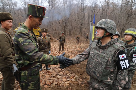 남북군사당국이 '판문점선언 이행을 위한 군사분야 합의서'에 따라 공동유해발굴의 원활한 추진을 위해 강원도 철원 '화살머리고지' 일대에서 남북 도로개설을 추진하고 있는 가운데, 2018년 11월 22일 도로연결 작업에 참여한 남북인원들이 군사분계선(MDL) 인근에서 인사하고 있다.<div id='ad_body3' class='mbad_bottom' ></div> 사진=국방부 제공