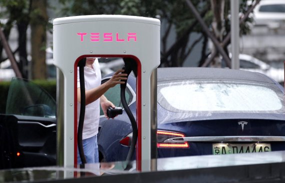 FILE PHOTO: A man finishes to charge his Tesla car at a charging point outside Tesla China headquarters in Beijing, China July 11, 2018. REUTERS/Jason Lee/File Photo /사진=연합 지면외신화상