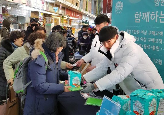 KT가 지난 15일 서울 마포구 망원시장에서 소상공인 지원 온마켓 행사를 진행하며 시장 방문 고객들에게 장바구니와 온쫄면, 온음료 등을 나눠주고 있다.