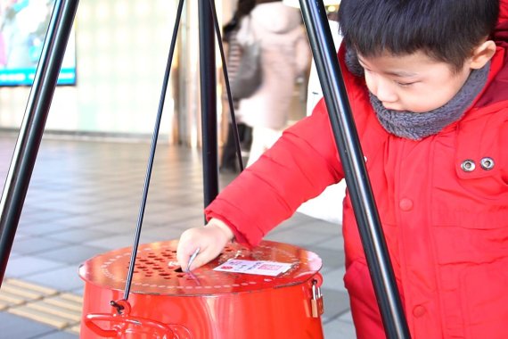 지난 크리스마스 이브에 서울 서울역 광장에 설치된 자선냄비에 한 어린이가 기부하고 있다. 사진=해당 영상 갈무리