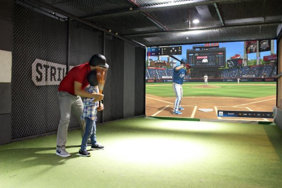 스크린야구장 '스트라이크존'에서 아버지가 아이에게 야구를 가르쳐주고 있다. 뉴딘콘텐츠 제공