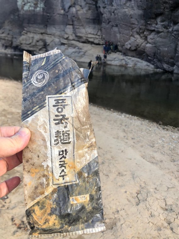 반구대암각화 앞 모래톱에서 발견된 풍국면 맛국수 비닐포장 앞 /사진=최수상 기자