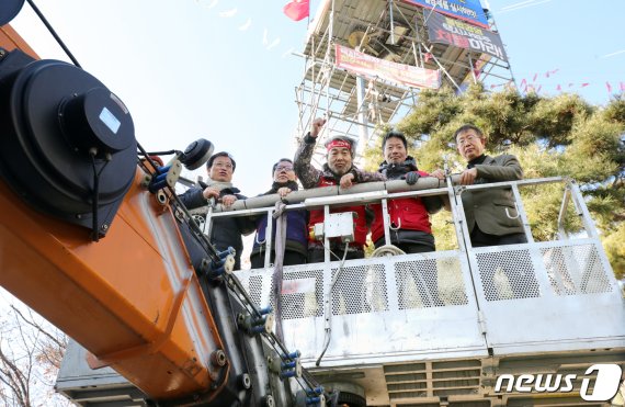 전주시청 조명탑 고공농성장에서 510일째 농성을 이어가던 김재주 공공운수노조 택시지부 전주지부장(왼쪽 세번째)이 26일 전북 전주시 전주시청에서 전주시와 공공운수노조 택시지부간의 전액관리제 협상이 타결된 뒤 크레인을 타고 농성장에서 내려오며 주먹을 불끈 쥐고 있다.20