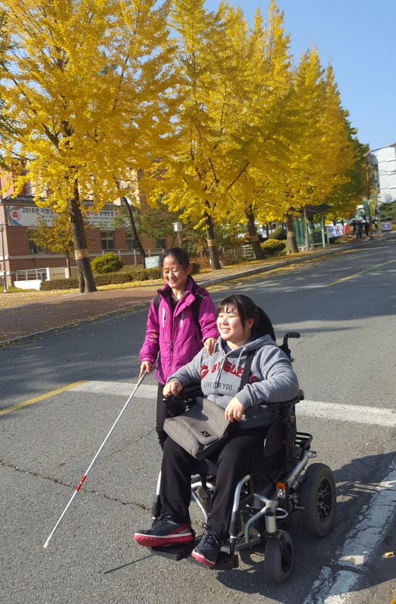 지팡이를 짚은 김하은씨(시각장애)와 휠체어를 탄 설진희씨가 함께 캠퍼스를 거닐고 있다. 사진=대구대 제공