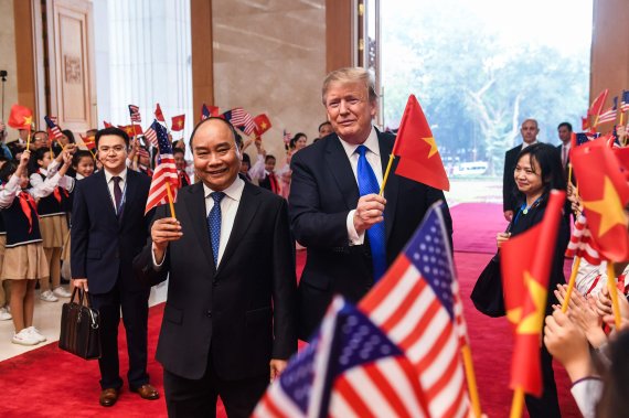 북한과 2차 정상회담을 위해 베트남을 방문한 도널드 트럼프 미국 대통령(오른쪽 첫번째)이 2월 27일 수도 하노이의 정부청사에서 응우옌 쑤언 푹 베트남 총리와 함께 양국의 국기를 바꿔 흔들고 있다.AFP연합뉴스