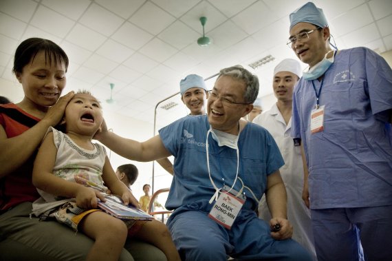 백롱민 교수가 치료를 끝낸 아이를 살펴보며 환하게 웃고 있다.