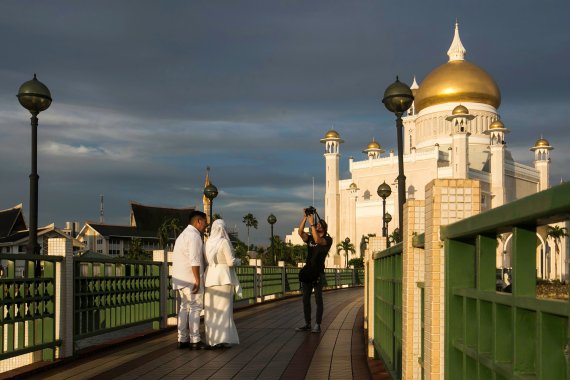 In this picture taken on April 1, 2019 a newlywed couple has their photographs taken at the Sultan Omar Ali Saifuddien mosque in Bandar Seri Begawan. - The United Nations decried on April 1 new 'cruel and inhuman' laws set to take effect in Brunei this week which impose death by stoning for gay sex 