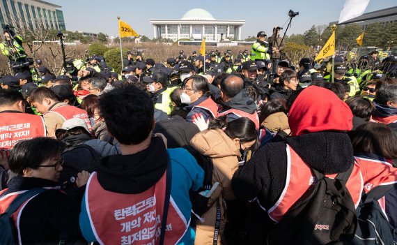 3일 오전 국회 정문 앞에서 시위 중인 민주노총 조합원들이 노동관련법 개악 저지 등을 요구하며 정문 담장을 부수고 국회 경내 진입을 시도하자 경찰병력이 이를 저지하고 있다. 국회 환경노동위원회는 이날 고용노동소위원회를 열고 탄력근로제 단위기간 확대를 위한 '근로기준법 개정안'과 최저임금 결정체계 이원화를 골자로 한 '최저임금법 개정안'을 심사했지만 여야 간 의견 차로 진통을 거듭했다. 사진=박범준 기자