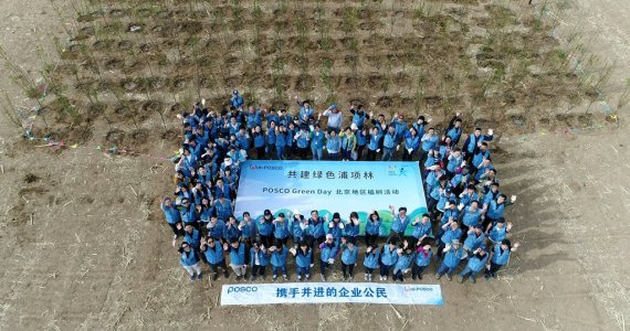 포스코 중국 현지 임직원들이 지난 18일 베이징 인근 생태보존지역의 식수단지에서 식수행사를 마친 뒤 단체사진을 찍고 있다. 포스코 제공