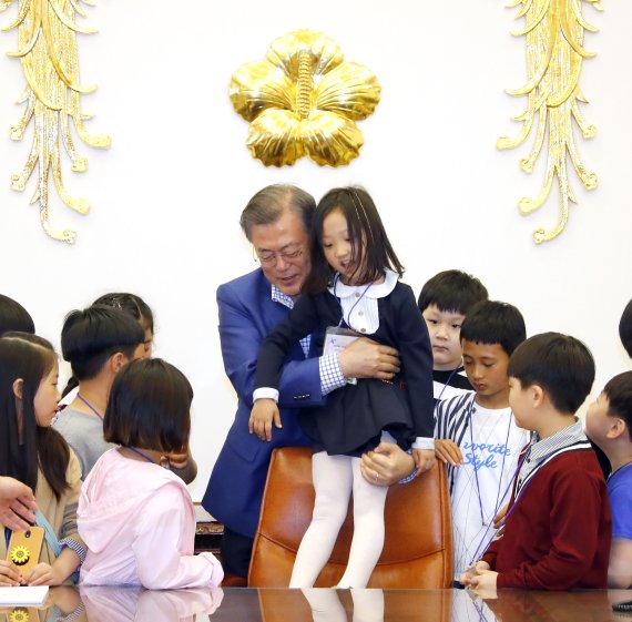 문재인 대통령이 어린이날인 5일 오전 청와대 집무실에서 강원도 산불진화 소방관 자녀와 산불 피해 초등학교 학생들과 함께 기념촬영을 하던 중 한 어린이를 대통령 의자에 앉히고 있다. 이날 청와대는 강원도 산불진화 소방관, 군인, 경찰 자녀와 산불 피해 초등학교 학생 및 아동정책 수혜 아동, 독립유공자 후손 등 총 180명의 어린이를 청와대로 초청해 행사를 열었다. 사진=연합뉴스