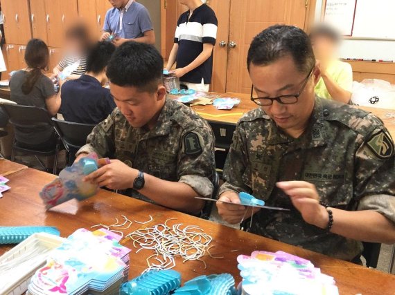 박주현 원사(오른쪽)가 아들 박수형 씨(왼쪽, 당시 상병)와 휴가기간 중 장애인복지관에서 장애인 직업능력 강화훈련 도구를 제작하는 모습 / 사진=육군 제공