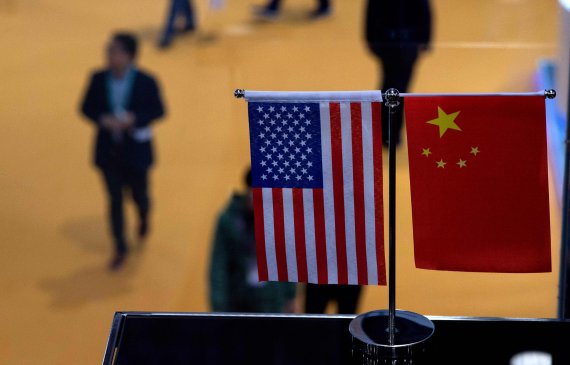 This file picture taken on November 6, 2018 shows a Chinese and US flag at a booth during the first China International Import Expo (CIIE) in Shanghai. - With the eyes of the world on Washington for the high-stakes trade talks on May 11-12, 2019 between China and the United States, none will be more