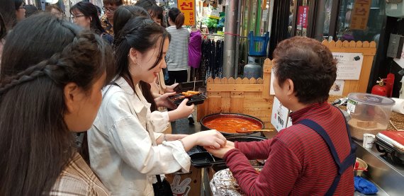 통인시장을 찾은 국내 관광객들이 엽전을 이용해 떡볶이를 사고 있다. 엽전 도시락은 통인시장의 트레이드 마크로 자리잡았다. 사진=김관웅 기자