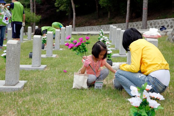 현대엔지니어링 임직원 가족 봉사자가 지난 18일 서울 동작구 국립현충원에서 묘비를 닦고 있다.