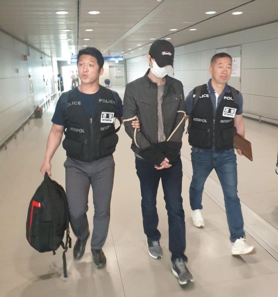지난 17일 김포국제공항에서 경찰관들이 일본 오사카로 도피했던 음란물 유포사범 고모씨(34)를 강제 송환하고 있다. 경찰청 제공