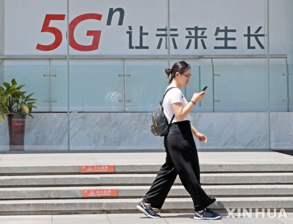 지난 3일 중국 베이징 도심에서 한 여성이 '미래 성장을 해 5G 발전'이라는 문구가 적힌 광고문 앞을 지나고 있다.신화뉴시스