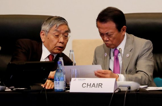 구로다 하루히코 은행은행(BOJ)총재(왼쪽)와 아소 다로 일본 부총리 겸 재무상이 지난 2019년 G20 재무장관 중앙은행 총재 회의에 참석해 나란히 앉아 대화를 나누고 있다. 로이터 뉴스1