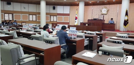 18일 고양시의회 본회의장에서 자유한국당 시의원들만이 노트북에 3기 신도시 철회 내용의 카드를 부착한 채 자리에 앉아 있다. © 뉴스1
