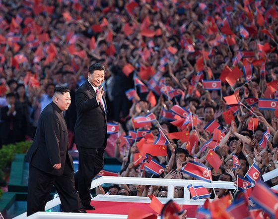 시진핑 중국 국가주석(오른쪽)이 김정은 북한 국무위원장과 함께 20일 북·중 우호를 주제로 한 집단체조를 관람하기 위해 방문한 평양 능라도 5·1경기장에서 환호하는 북한 관중을 향해 손을 들어보이고 있다. 신화AP뉴시스