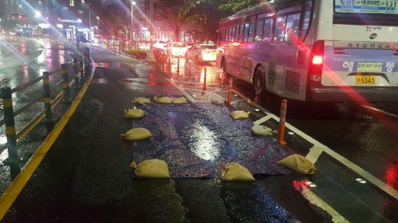 ▲ 26일 오후 5시 56분께 부산 해운대구 우동 운촌버스정류장 BRT 구간 도로에서 포트홀이 발생했다. 해운대구청은 비가 그치는 대로 굴착작업을 통해 사고 원인 규명에 나선 뒤 도로를 복구할 방침이다./사진=부산지방경찰청 제공