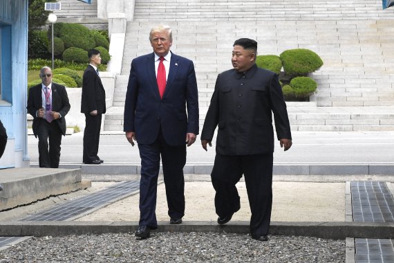 도널드 트럼프 미국 대통령(왼쪽)과 김정은 북한 국무위원장이 6월 30일 판문점에서 함께 군사분계선을 넘어 남쪽으로 향하고 있다.AP뉴시스
