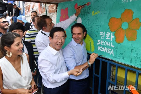 【서울=뉴시스】중남미를 순방중인 박원순 서울시장이 11일(현지시각) 콜롬비아 메데진 산비탈 빈민가 코무나13(Comuna13) 지역 주민들의 이동편의를 위해 설치된 384m 길이 에스컬레이터 대중교통 현장을 방문해 평화의 벽에 “평화 SEOUL KOREA"란 메시지를 직접 쓰고 있다. 2019.07.12. (사진=서울시 제공) photo@newsis.com
