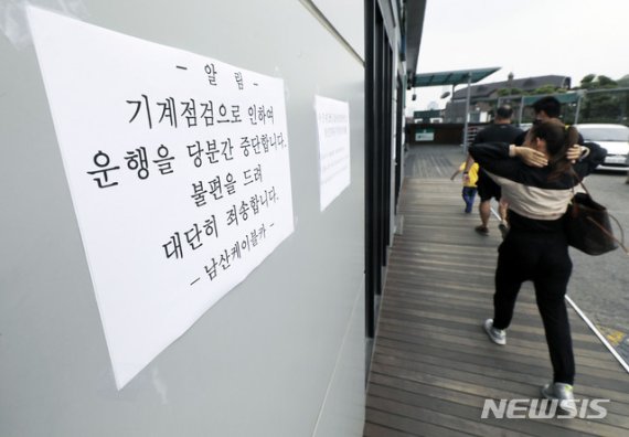 【서울=뉴시스】최동준 기자 = 13일 서울 중구 남산케이블카 매표소에 운행 중단을 알리는 문구 앞으로 외국인 관광객들이 발길을 돌리고 있다.지난 12일 발생한 사고와 관련해 경찰은 당시 케이블카 운행제어 담당자를 입건할 예정이다. 2019.07.13. photocdj@newsis.com (사진=뉴시스DB)