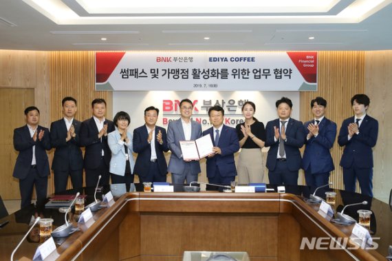 【부산=뉴시스】 제갈수만 기자 = BNK금융그룹 부산은행은 16일 오후, 문현동 본점에서 이디야커피와 ‘썸패스 및 가맹점 활성화를 위한 업무협약’을 체결했다.(사진 왼쪽에서 여섯번째부터 부산은행 한정욱디지털금융본부장, 이디야커피 최홍수 부사장) 2019.07.17, (사진= 부산은행 제공)photo@newsis.com