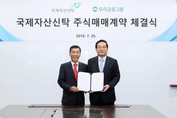 우리금융은 지난 25일 서울 종로구 법무법인 세종 회의실에서 국제자산신탁 경영권 지분 인수를 위한 주식매매계약(SPA)을 체결했다. 손태승 우리금융그룹 회장(오른쪽)과 유재은 국제자산신탁 회장이 기념촬영을 하고 있다.