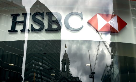 FILE - In this Tuesday, June 9, 2015 file photo, the HSBC logo is seen through a window where buildings are reflected on to, at a branch in London. HSBC announced on Monday Aug. 5, 2019, the surprise departure of CEO John Flint after 18 months in the job, saying the bank needs new leadership. (AP Ph