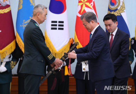 【서울=뉴시스】전신 기자 = 문재인 대통령이 지난 4월15일 청와대 본관에서 열린 군 장성 진급 및 보직 신고식에서 7군단장 윤의철 중장의 삼정검에 수치를 달아주고 있다. 2019.04.15. photo1006@newsis.com