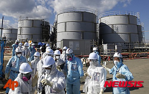 【오쿠마=AP/뉴시스】 2016년 2월 10일 보호복을 입은 기자들이 후쿠시마현 오쿠마에 있는 도쿄전력 원전의 방사성 물질 오염수 저장시설을 살펴보고 있다. 2016.03.08