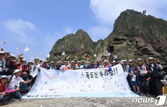 일본의 수출규제가 발동한 4일 오후 경상북도 울릉군 독도를 찾은 2019독도탐방 참가자들이 독도는 우리땅 글귀가 적힌 핸드프린팅 대형현수막과 함께 기념촬영을 하고 있다. 한국해양재단 주최로 열린 독도탐방에는 한국사진작가협회와 한국프로사진협회 회원 50여명이 참석했다. 2019.7.4/뉴스1 © News1 박세연 기자