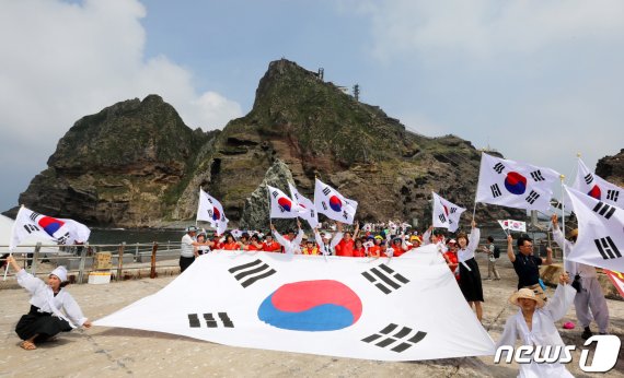 10일 경상북도 독도를 찾은 멀티암벽 산악회(대장 이재석, 엄재선, 차금호, 박경모) 오윤숙을 비롯한 대원이 독립운동가 의복을 입고 시민들과 함께 대형태극기를 펼치며 '한·일 경제위기&경제왜란, 하나되어 이겨냅시다' 퍼포먼스를 펼치고 있다. 2019.8.10/뉴스1 © News1 박세연 기자